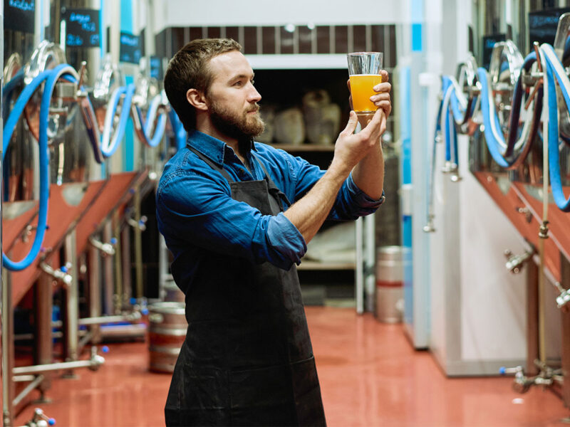 Man håller i ölglas på bryggeri
